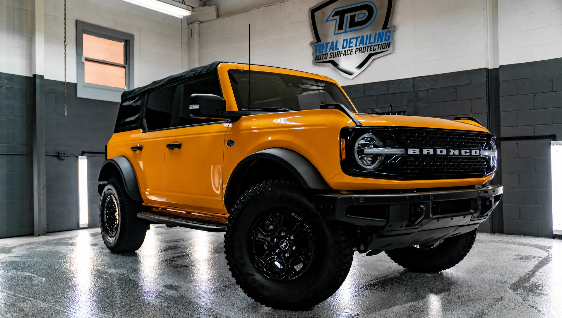 An orange SUV after detailing, paint and trim clean under the shop lights.
