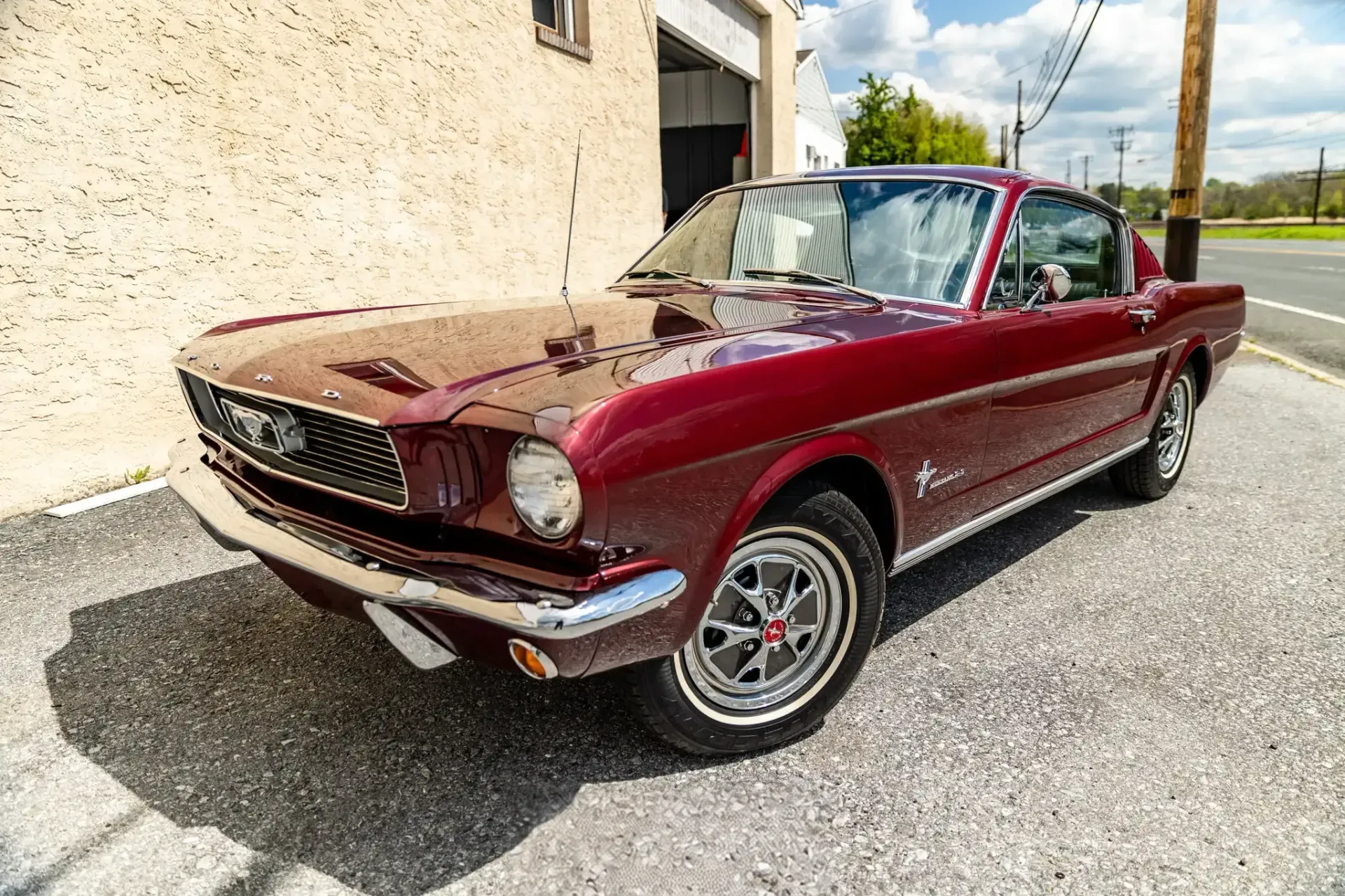 A maroon 1966 Mustang fastback parked outside the shop after a detail.