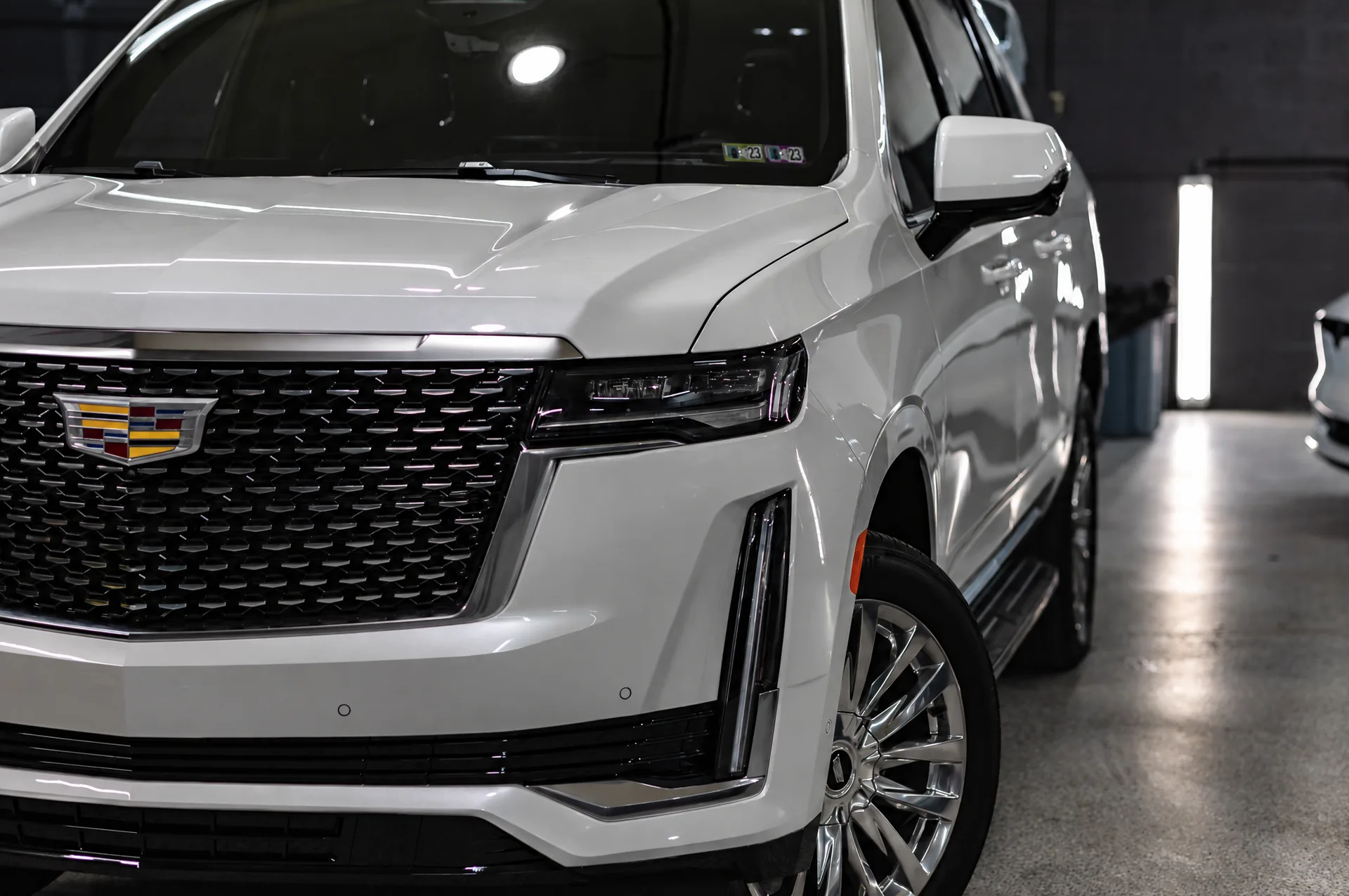 The front of a white SUV after detailing, grille and paint gleaming under the shop lights.