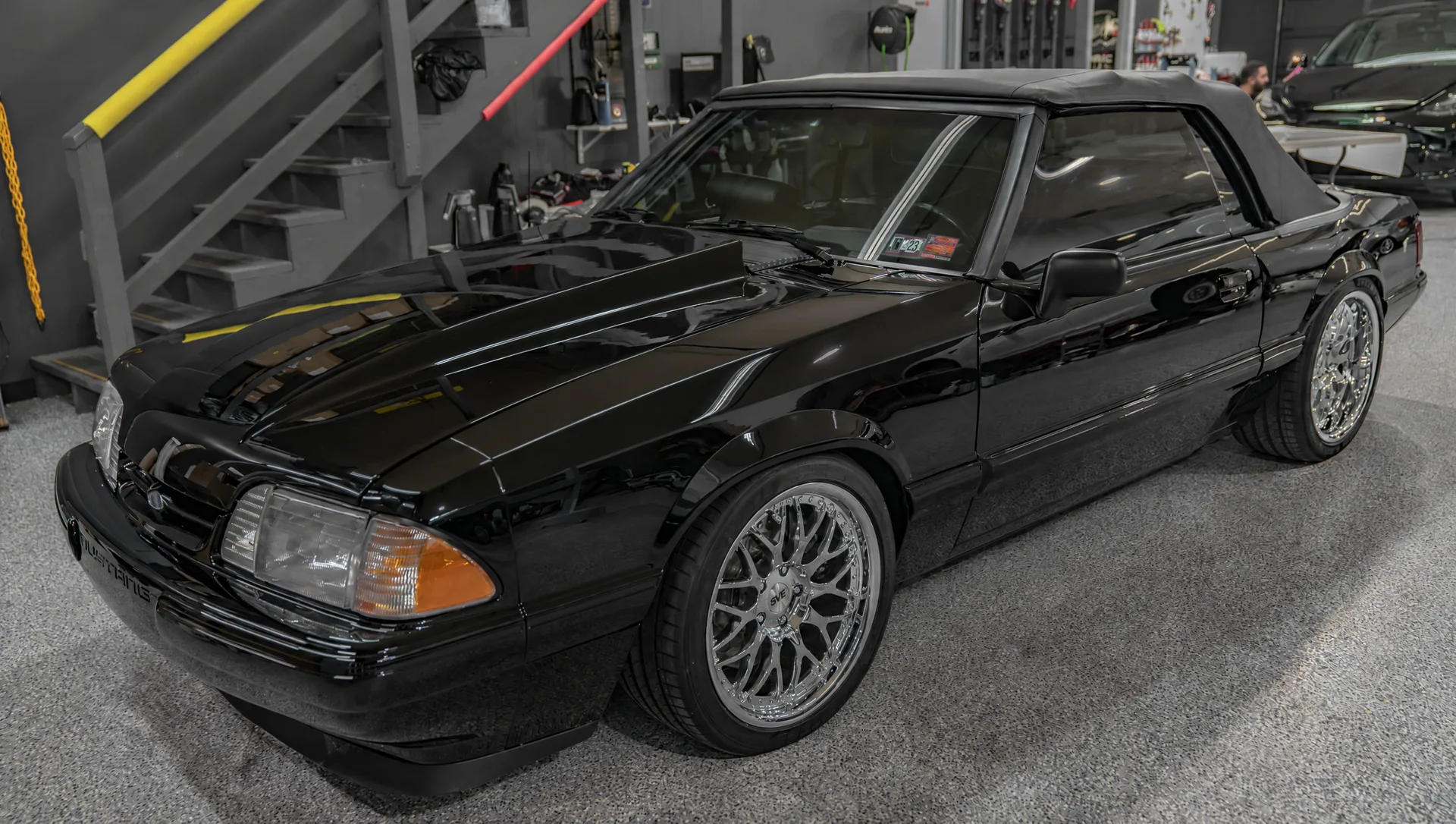 A black convertible after a Showroom detail, paint reflecting the shop lights.