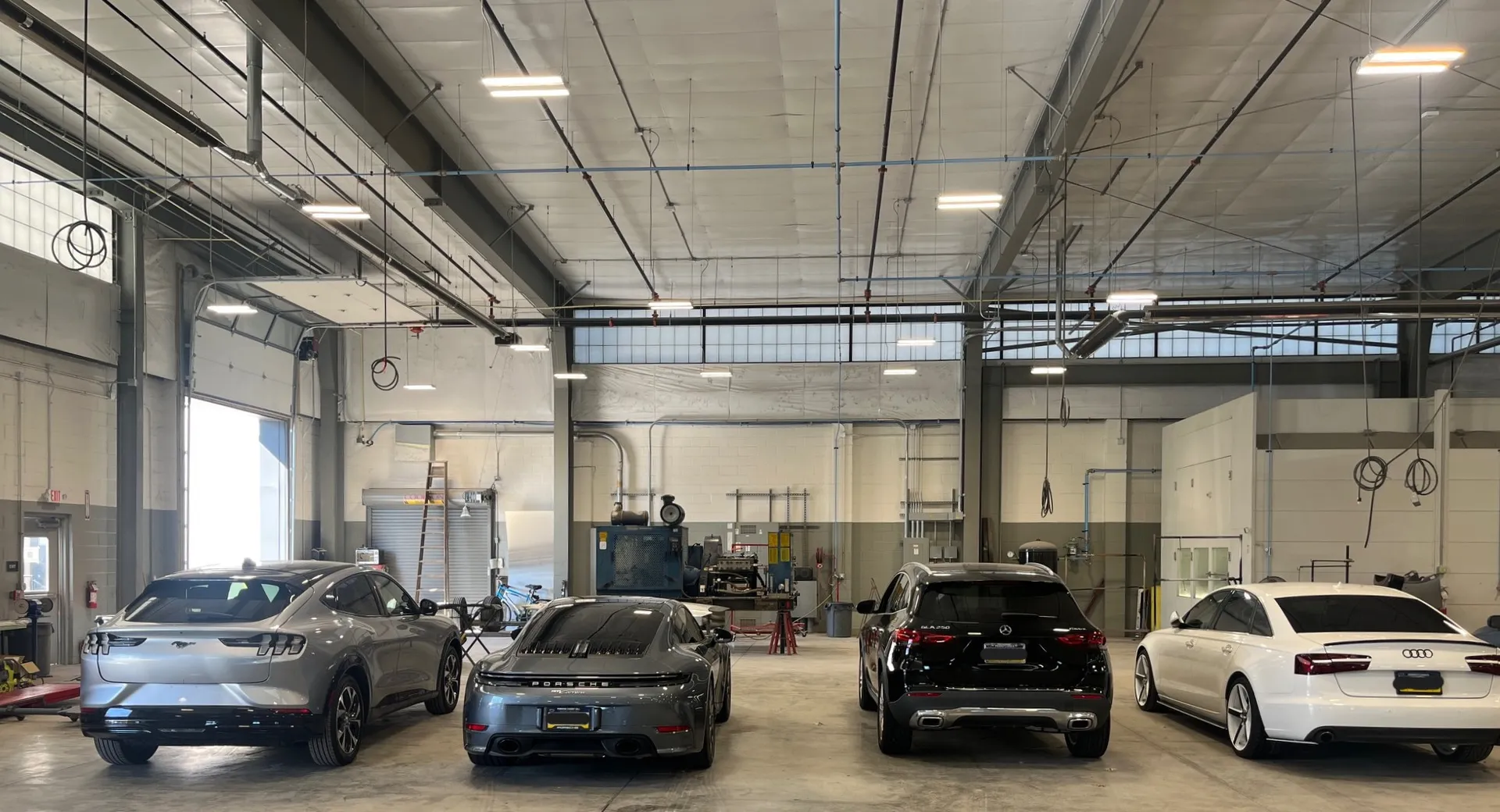 Four cars lined up inside the detail bay under the shop lights.