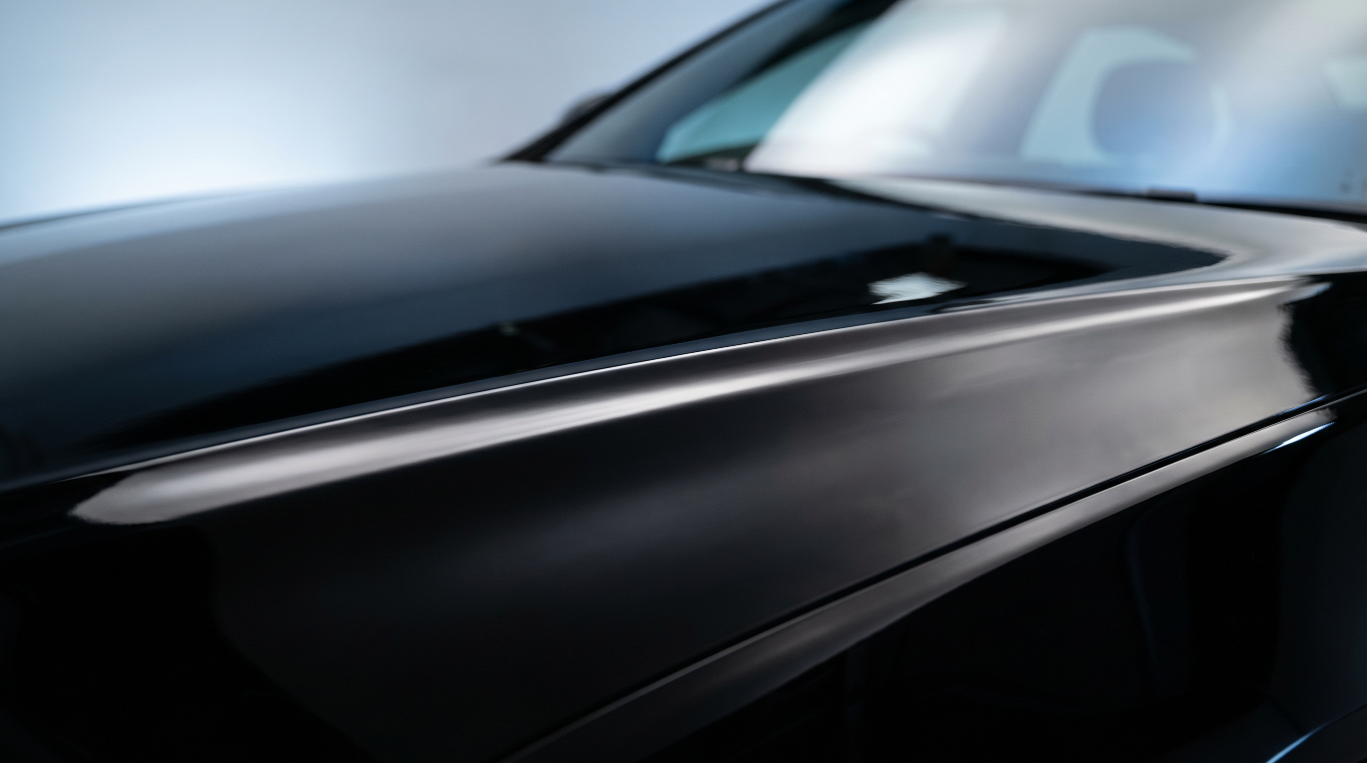 Deep, mirror-flat black paint under studio light after machine correction and coating