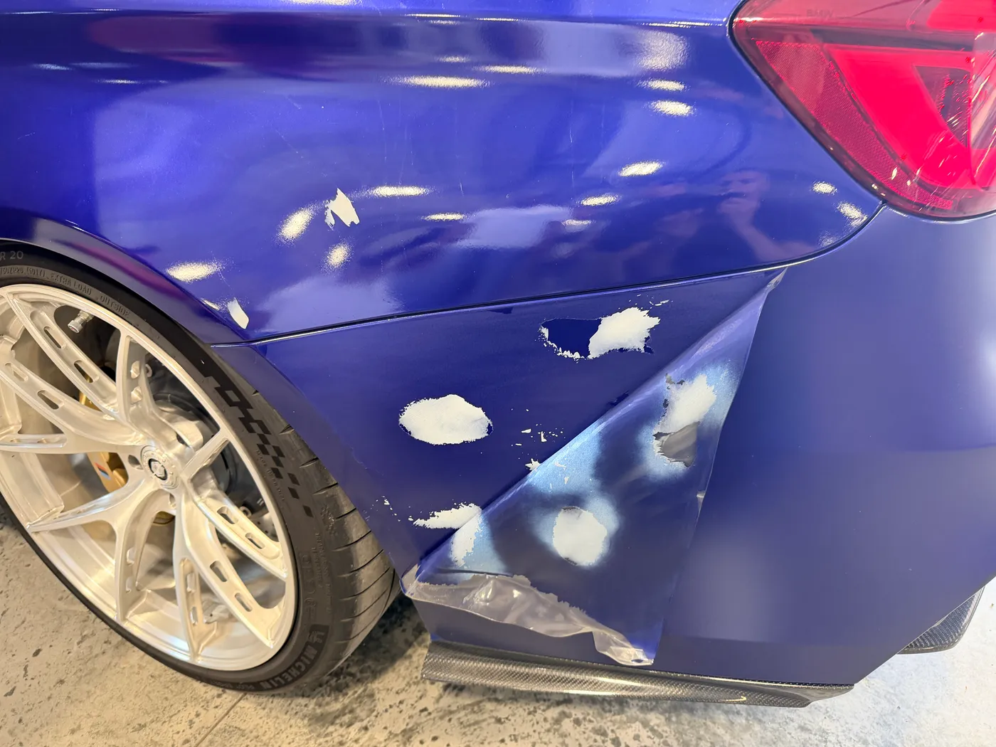 BMW fender with paint pulled away in patches where sheet film was removed