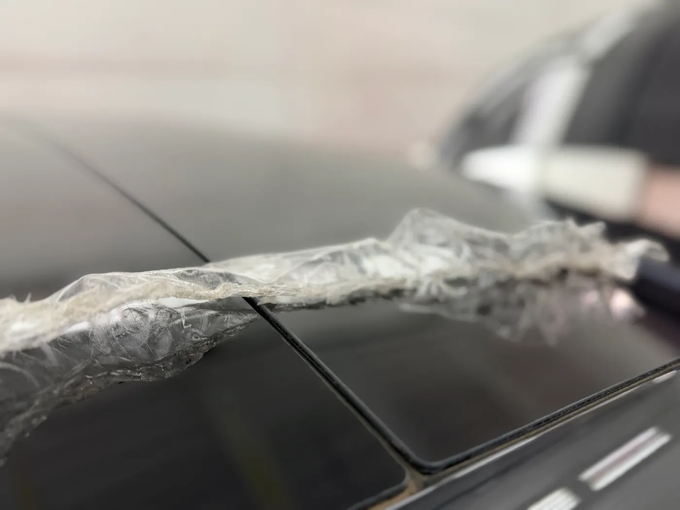 Sheet paint protection film tearing off a Lucid roofline in shredded ribbons during removal