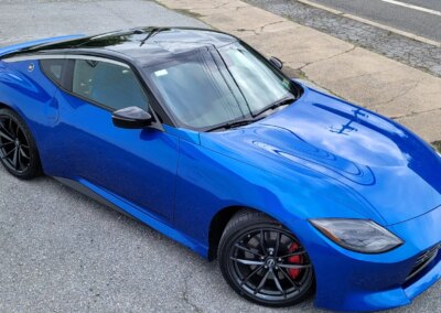A blue car with shiny detailing in a garage with equipment in the background.