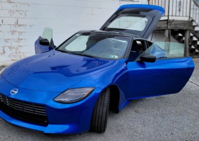 A clean, red sports car parked in a garage with detailing equipment in the background.
