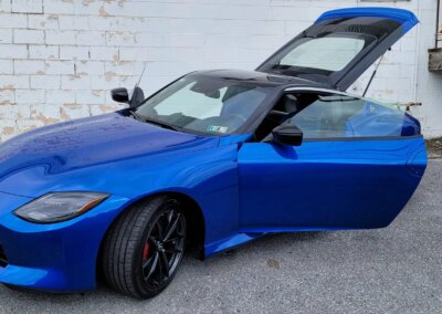 A car getting detailed at Total Detailing shop with worker polishing the hood.