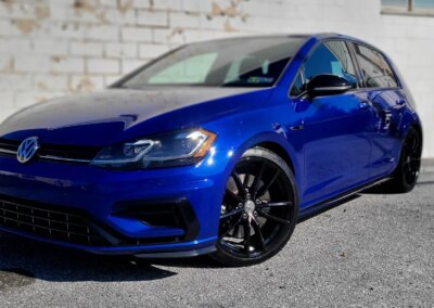 A black car parked on a driveway with its doors open, ready for detailing.