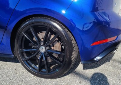 A shining black car after detailing service under bright sunlight.
