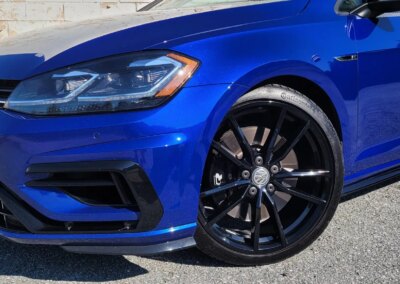 A car with open doors being detailed in a garage.