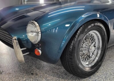 A shiny black car after detailing, parked on a concrete floor near a garage door.