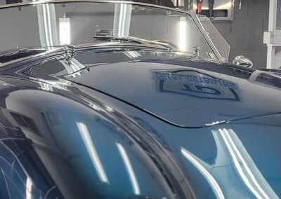 A car with shiny black paint receives a thorough detailing service.