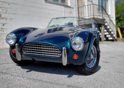 A shiny black car after professional detailing with a clear reflection on the hood.