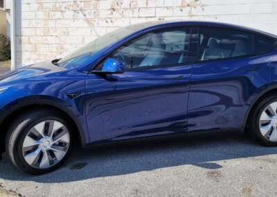 A close-up of a car's tire and rim being professionally detailed and cleaned.