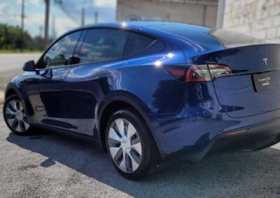 A shiny black car parked outside with trees in the background.