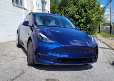 A shiny black car after detailing service with a clear reflection on its hood.