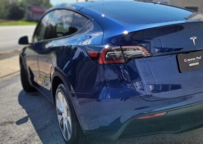 Car detailing professional applying protective coating to a black car's hood.
