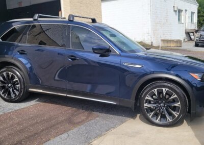 A silver car receiving a thorough detailing service in a well-lit garage.