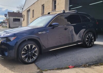 A shiny black car after detailing service with reflections on the hood.