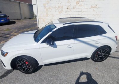 A car with a glossy finish being detailed by a worker using a polishing machine.