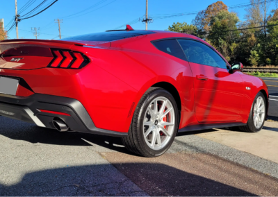A shiny red Mustang with a ceramic coating finish parked outdoors.