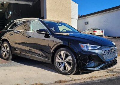 A shiny black car with a reflection on its hood after detailing.
