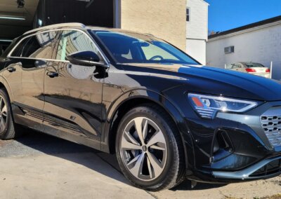 A shiny black car with a detailed finish parked in a garage.