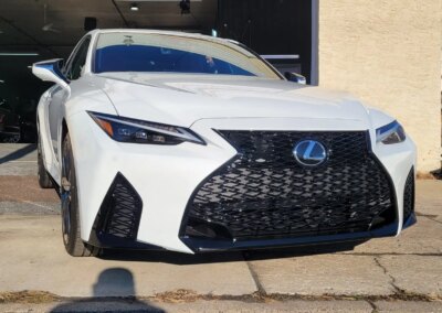 A blue car being detailed by a worker with a polishing machine in a garage.