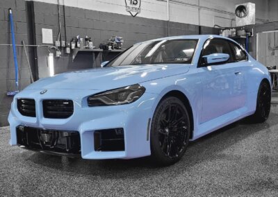 A red car being detailed by a worker in a garage.