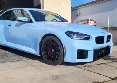 A car undergoing detailing with equipment and cleaning products nearby.