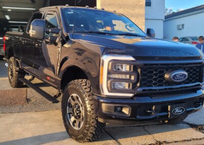 A car getting detailed by a worker with cleaning equipment.