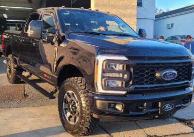 A red car undergoing detailing with cleaning equipment in a garage.