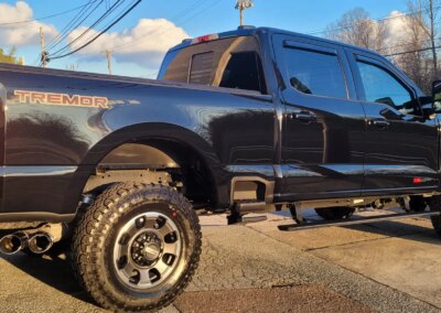 A red car being detailed by a worker with a polishing machine.