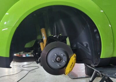 A car detailing technician polishing a black car's hood