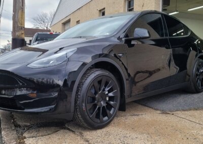 A shiny black car after detailing with reflections on the hood.