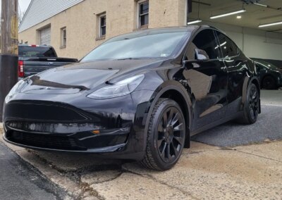 A car being detailed by a worker with cleaning equipment in a garage.