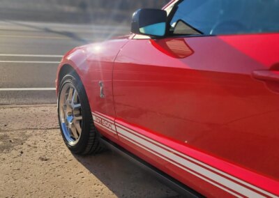 A car with a shiny black paint job being detailed by a professional.