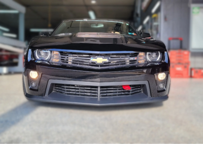 A car covered in soap suds being washed with a sponge.