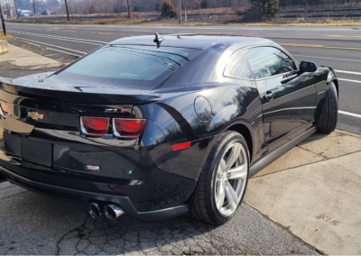 A man detailing a blue car with a microfiber cloth.