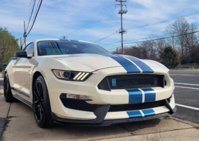 A black car being detailed with a polishing machine by a worker.
