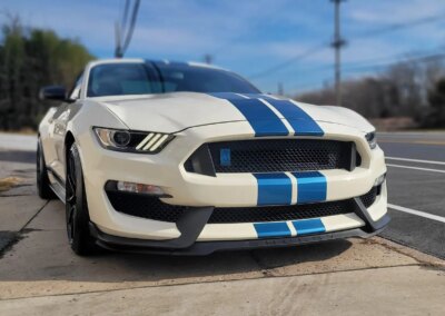 Car undergoing detailing with foam and water spray at Total Detailing shop.