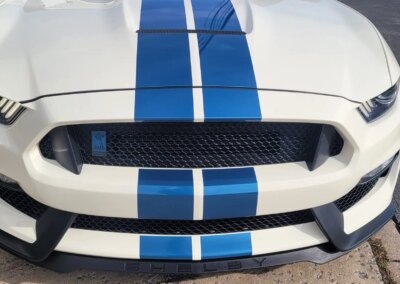 A person detailing a black car with a microfiber towel.