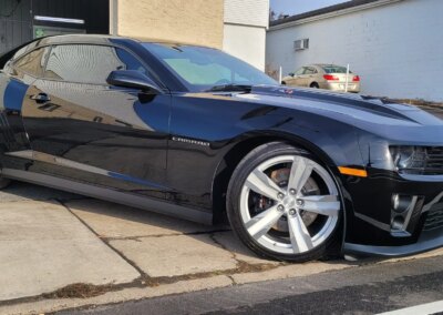 A blue car being washed with soap suds at a car detailing service.