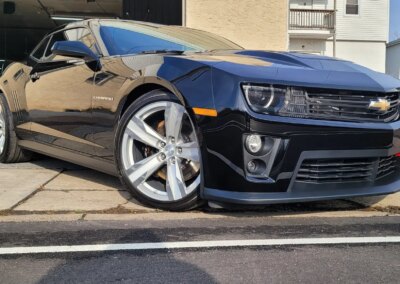 Car with lights on being detailed in a workshop.
